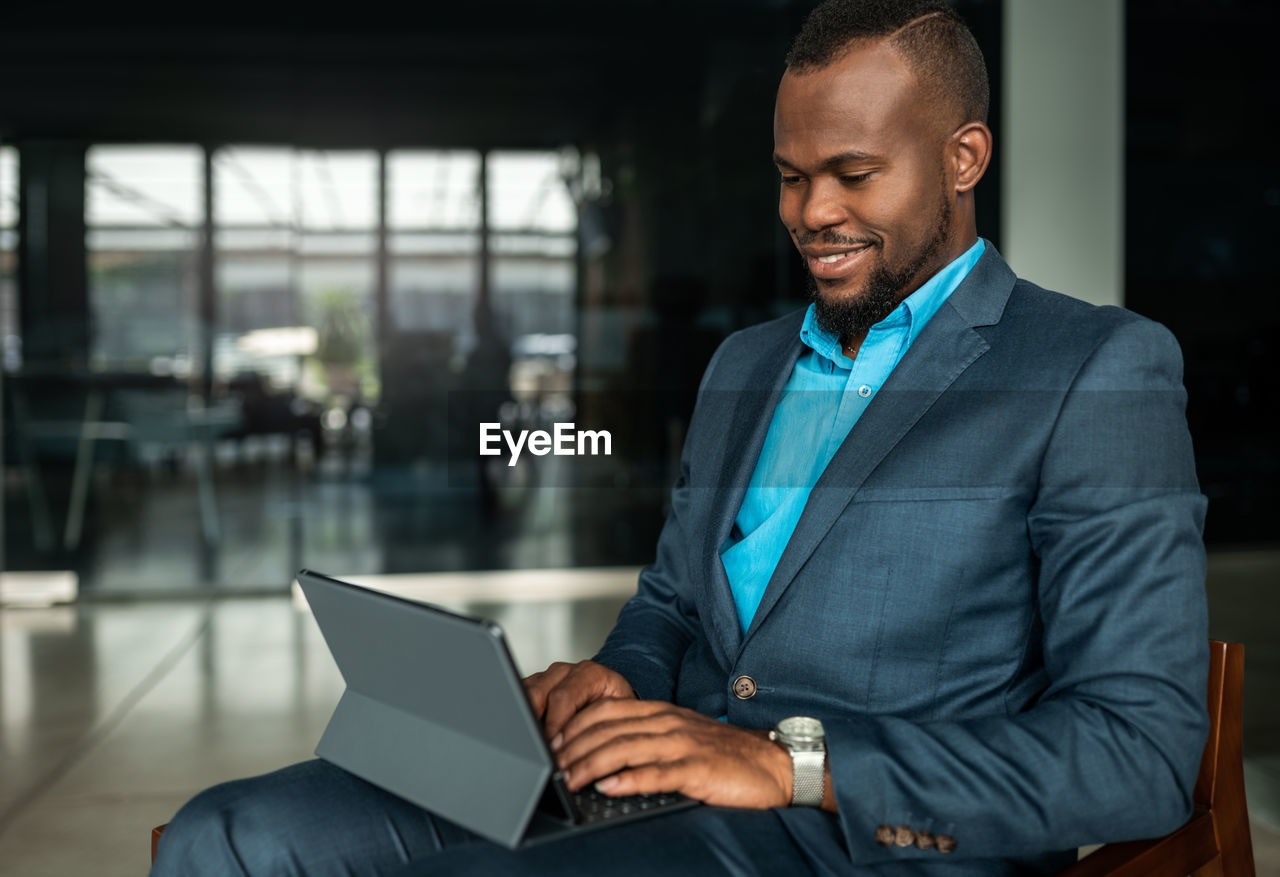 Businessman wearing suit using laptop while sitting at office