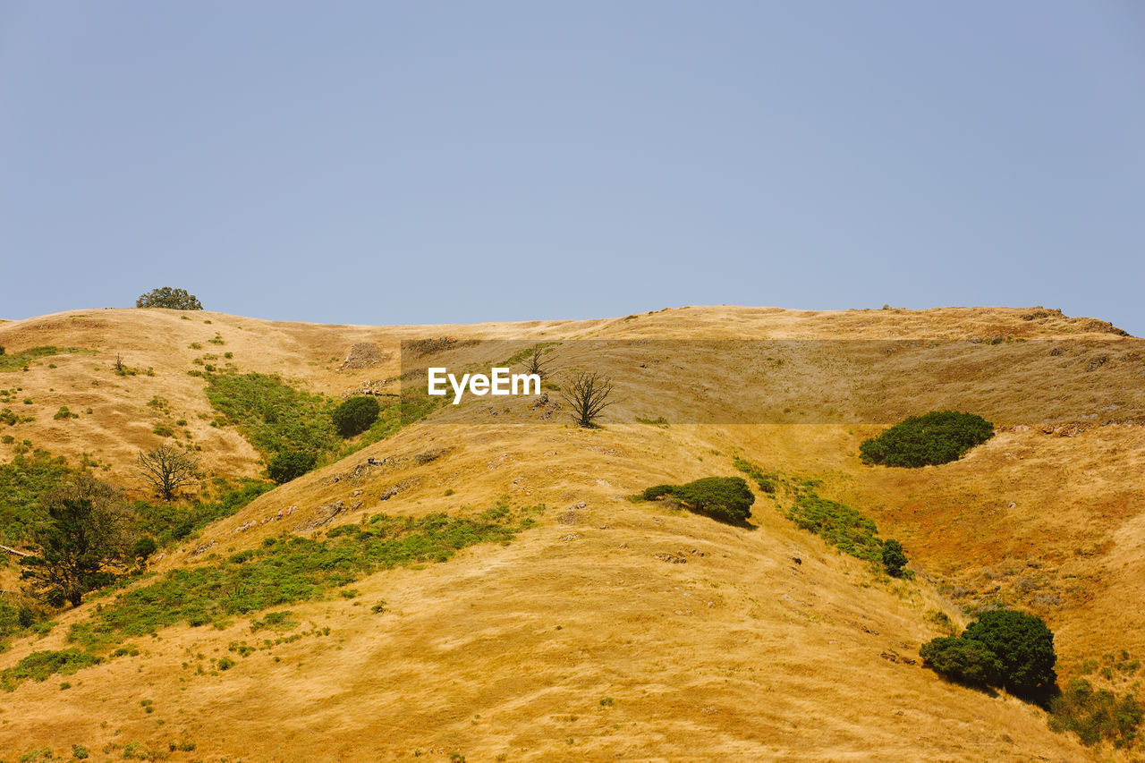 Low angle view of land against clear blue sky