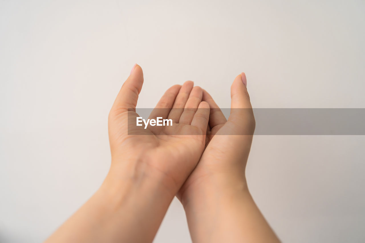 CLOSE-UP OF HAND OVER WHITE BACKGROUND