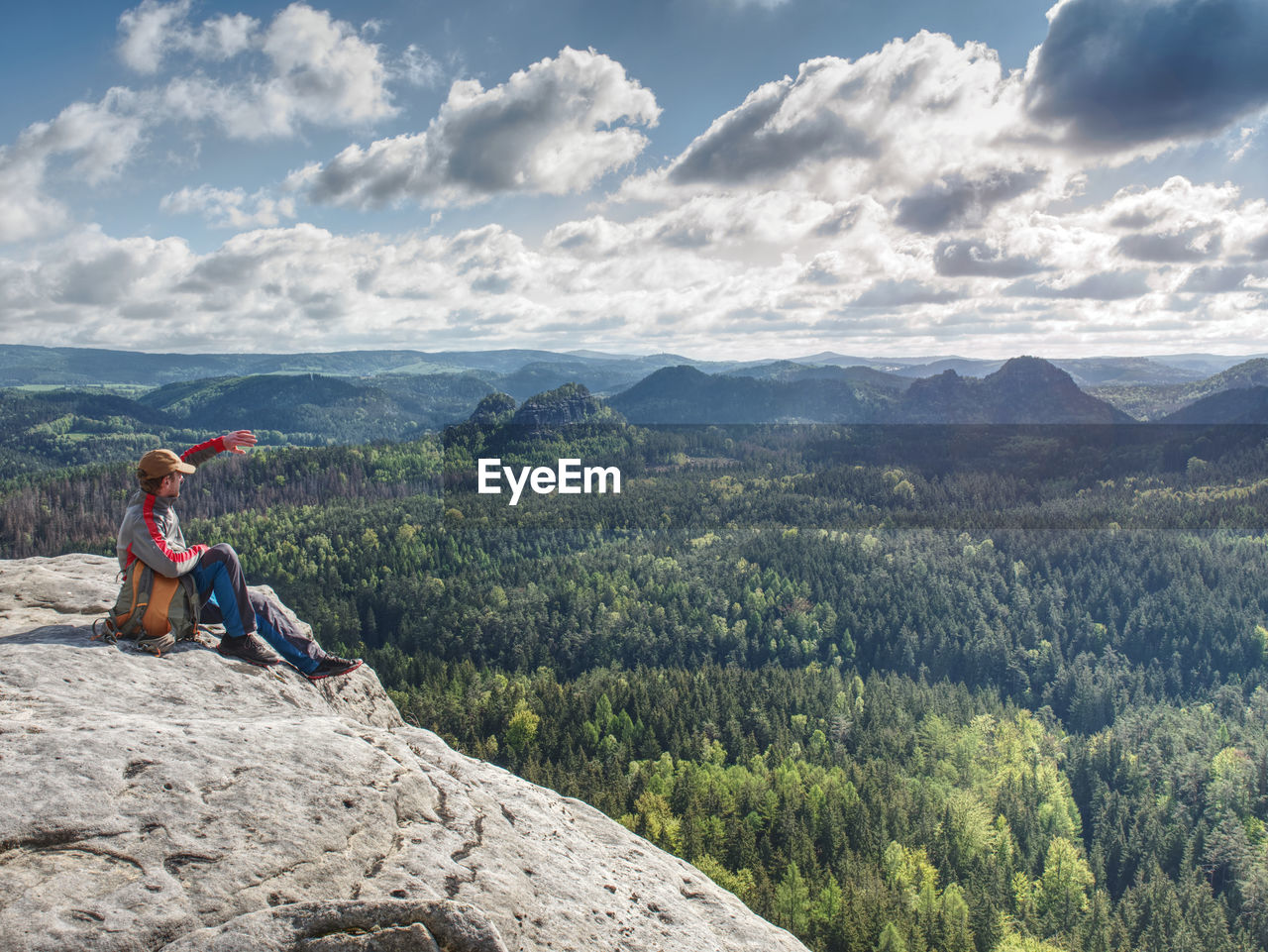 Male hiker meditating on flat place above valley. amazing view into pure nature. sunny spring day