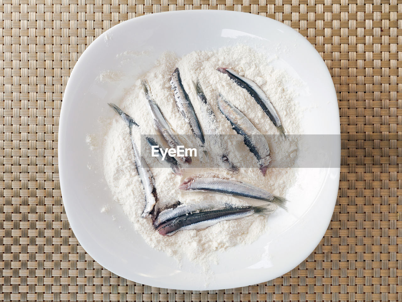 Directly above shot of anchovies on flour in plate at table