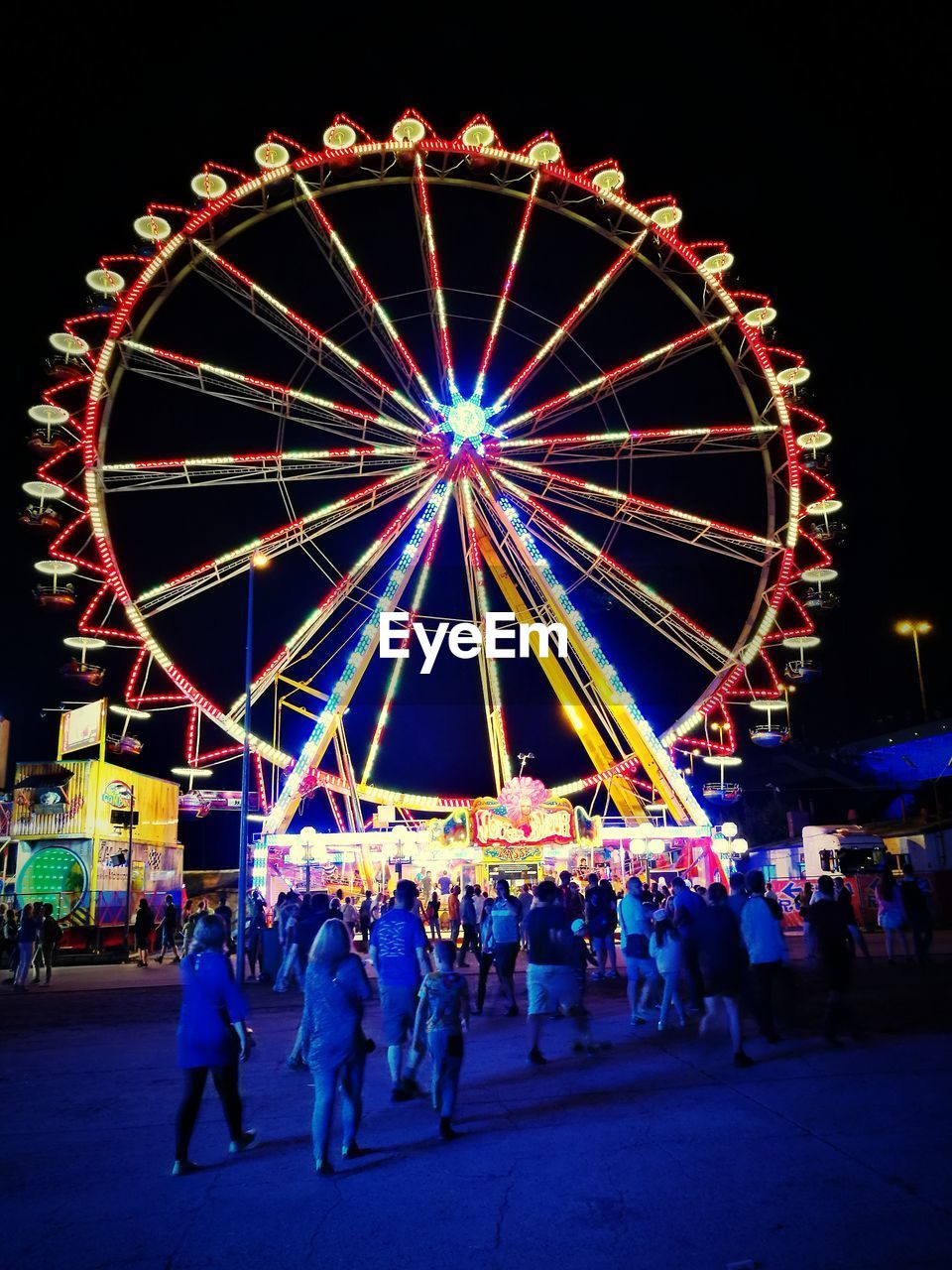 PEOPLE AT AMUSEMENT PARK AGAINST SKY AT NIGHT