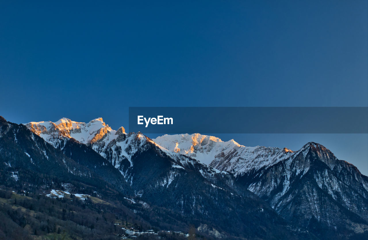 Scenic view of snowcapped mountains against clear blue sky