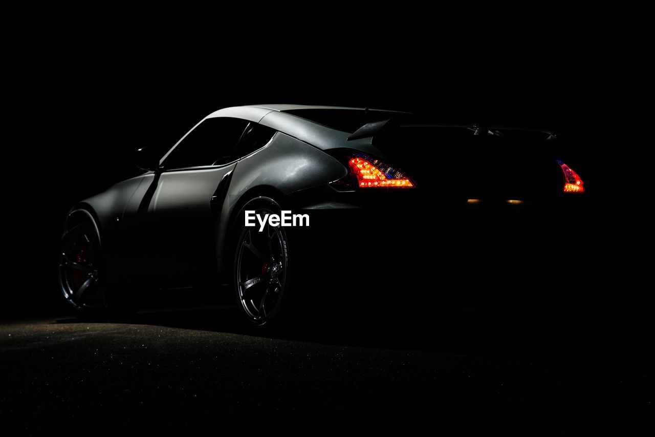 car, mode of transportation, vehicle, motor vehicle, transportation, land vehicle, sports car, automobile, black background, supercar, night, wheel, black, illuminated, luxury vehicle, performance car, speed, indoors, no people, studio shot, dark