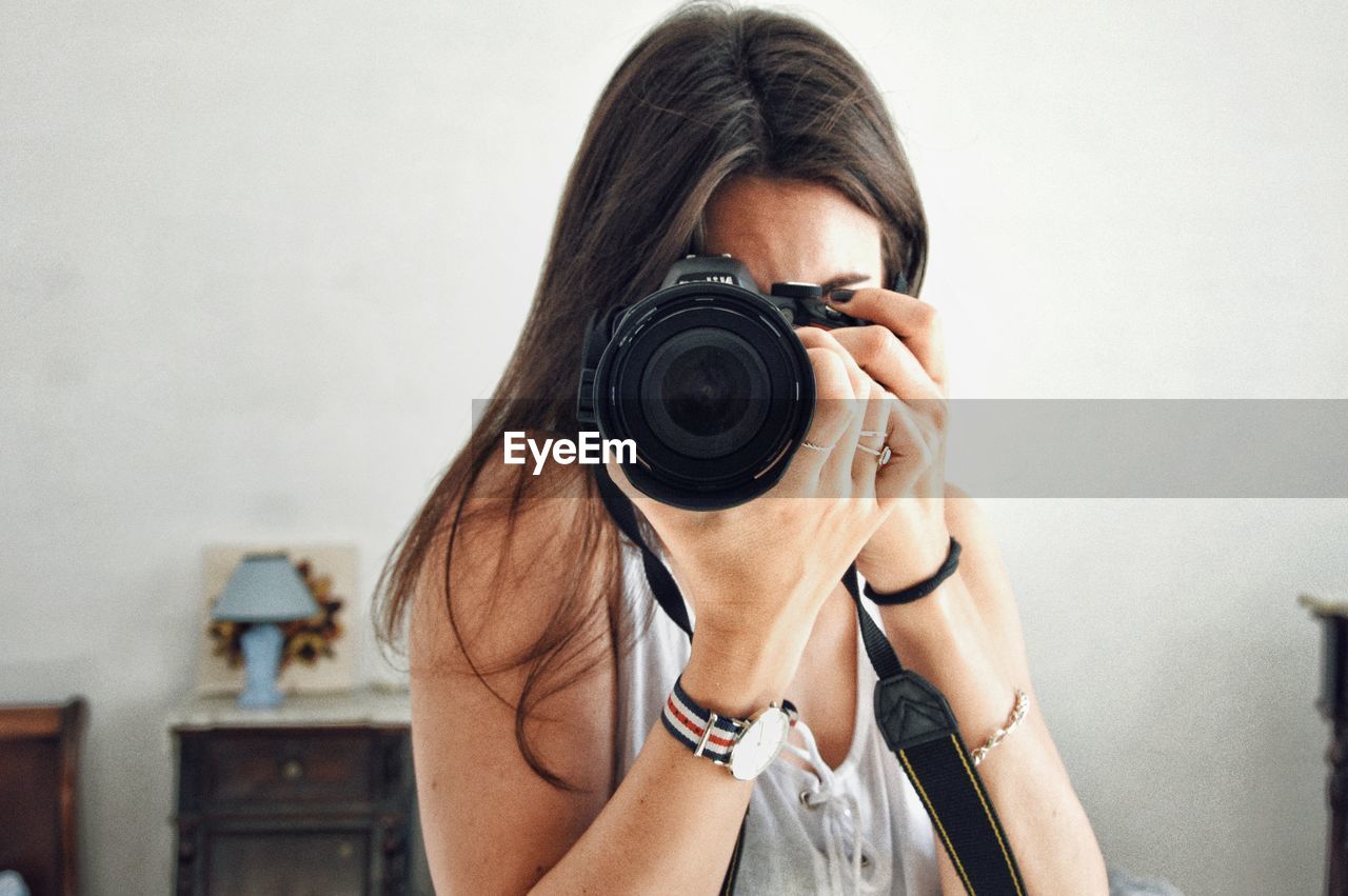 Close-up of woman photographing with camera at home