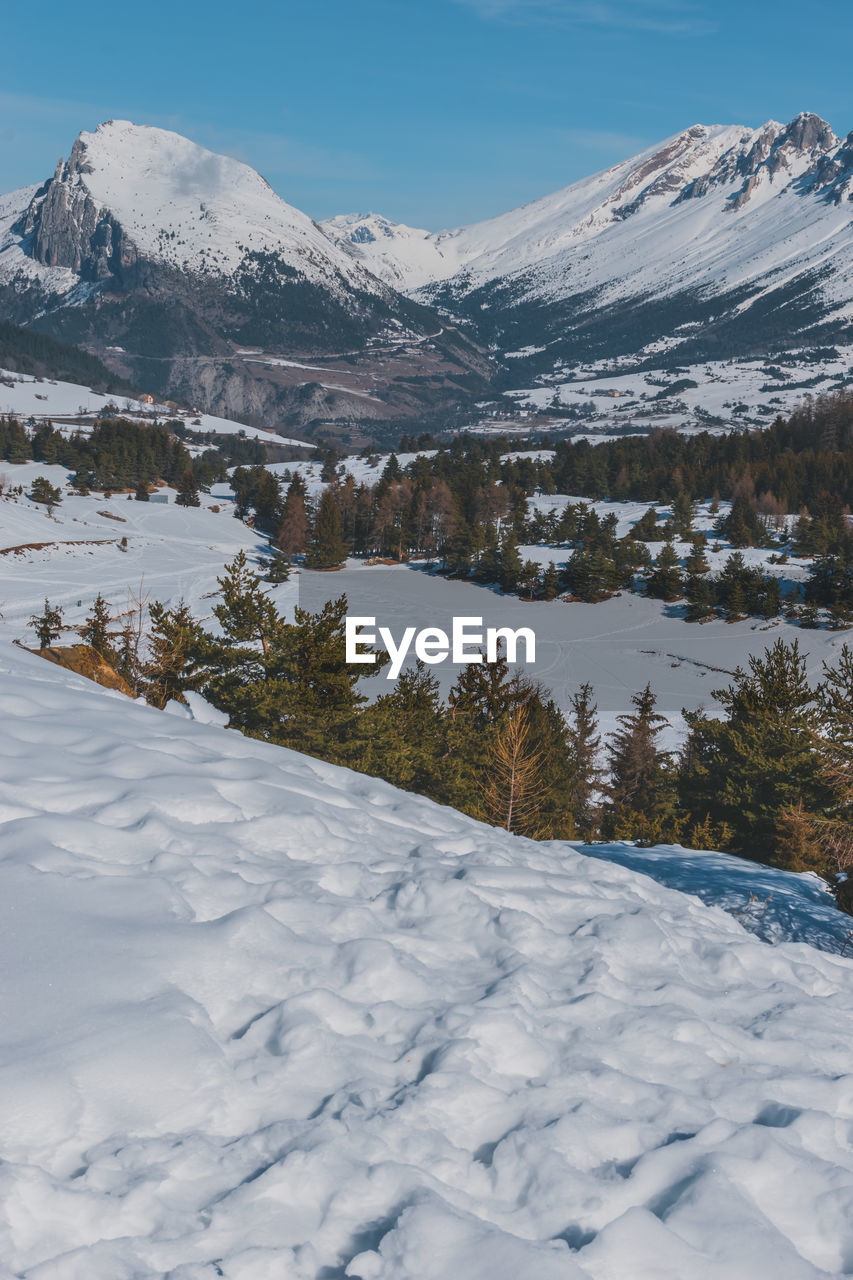 A picturesque landscape view of the snowcapped french alps mountains with a hiking path in the snow