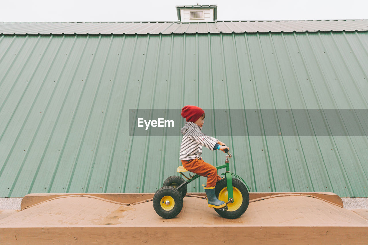 Side view of boy riding tricycle outdoors