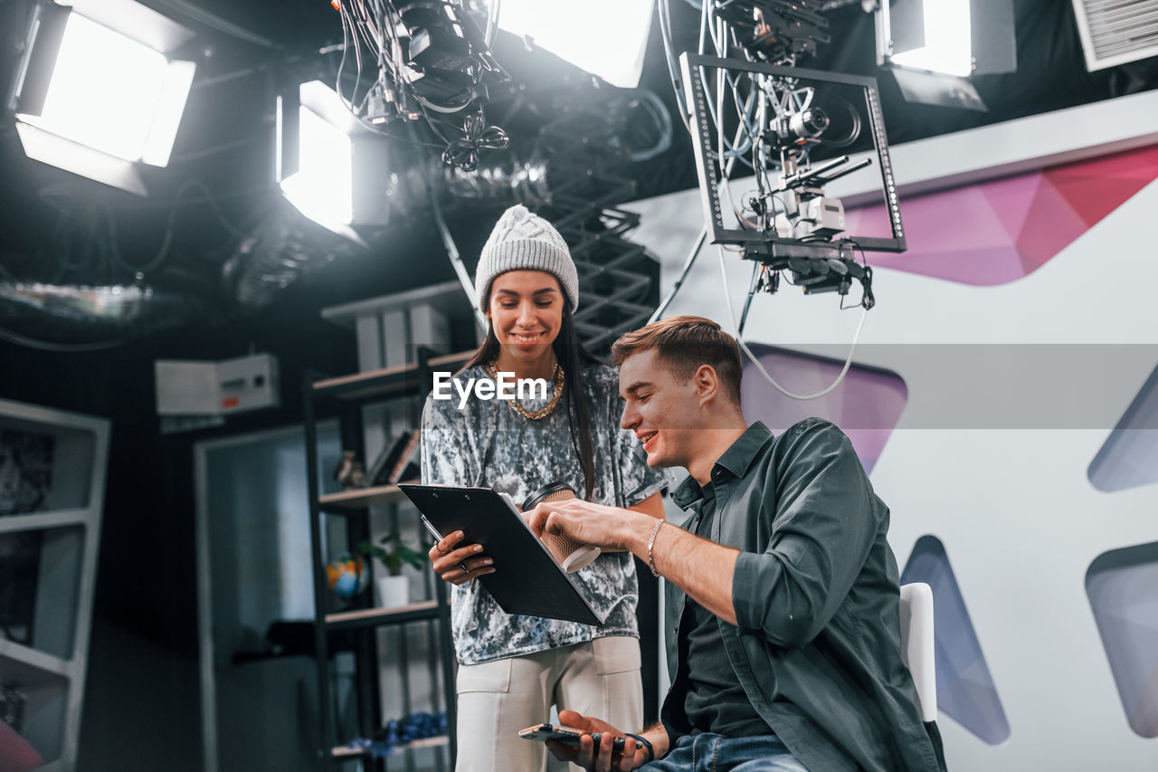 Young man is preparing for tv online broadcast. woman helps with make up.