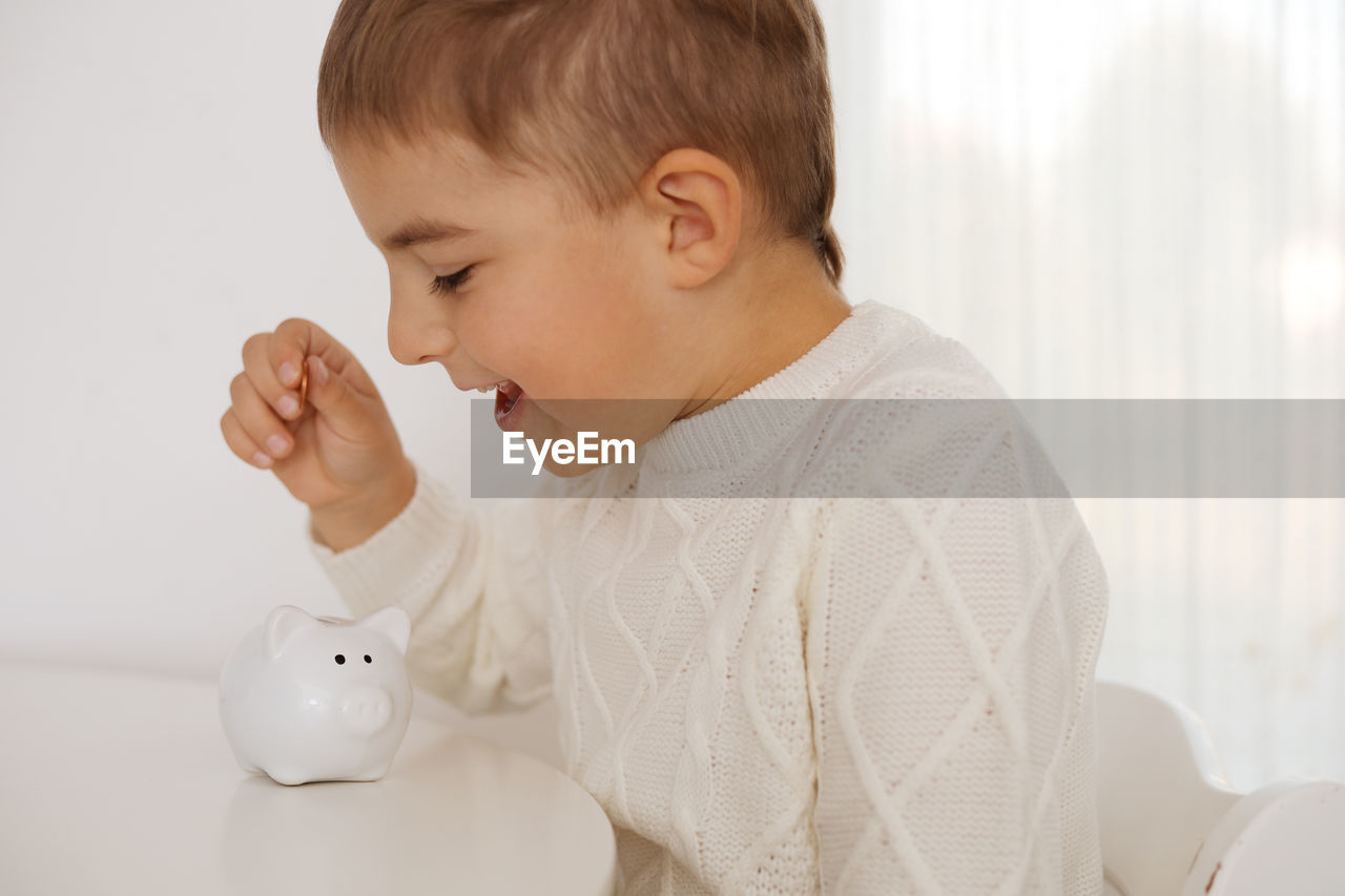 Little boy putting money coin into piggy bank for saving money. wealth, budget, investment, finance