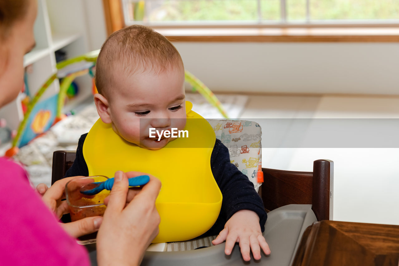 Rear view of boy using mobile phone at home