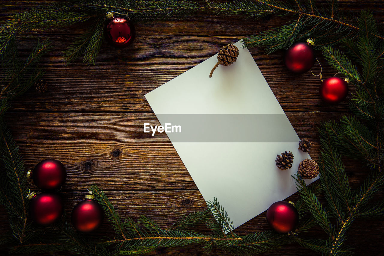 High angle view of christmas decorations with blank paper on wooden table