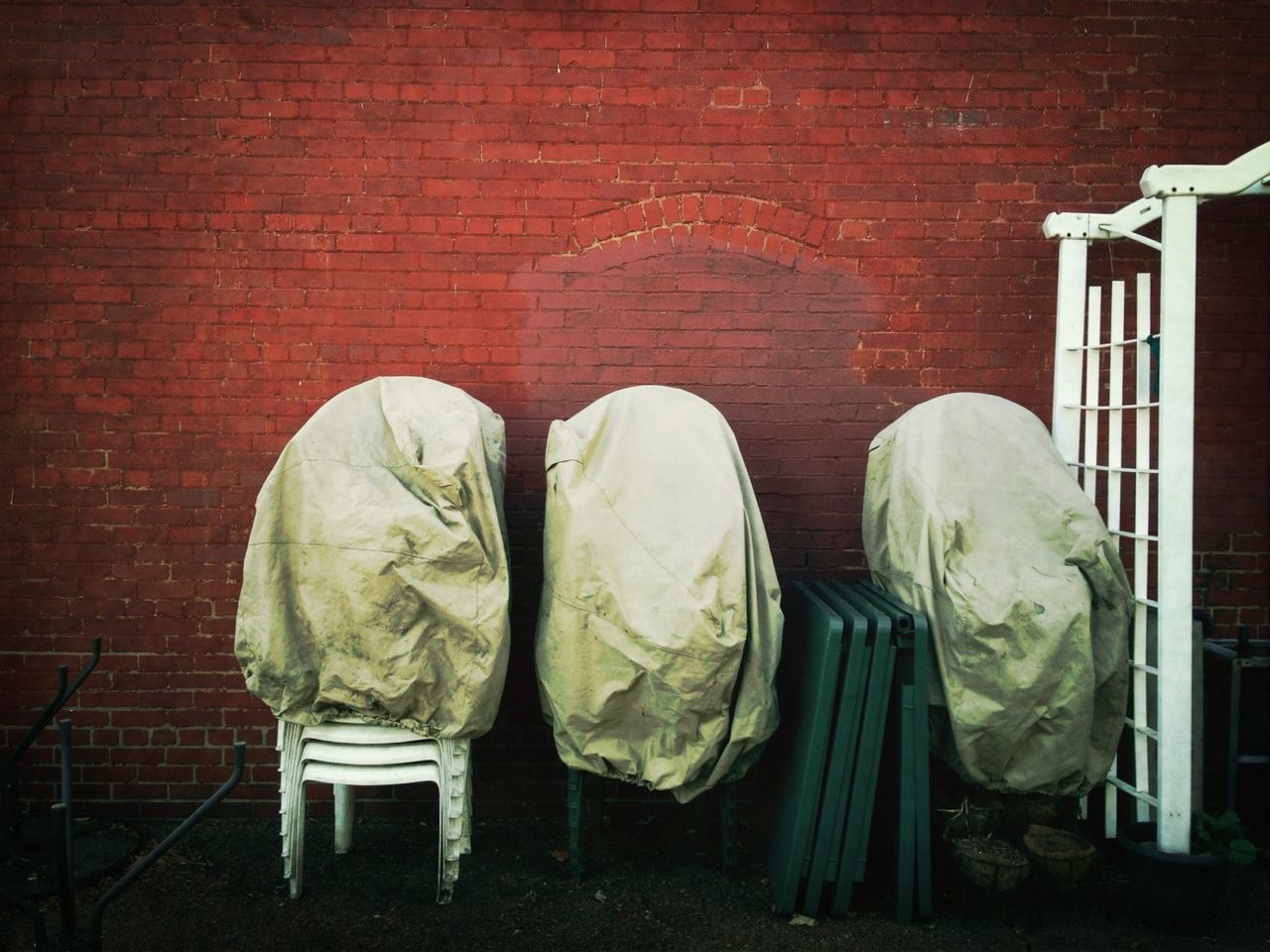Chairs covered with cloth against brick wall
