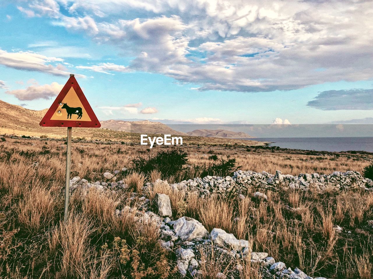 Road sign on landscape against sky