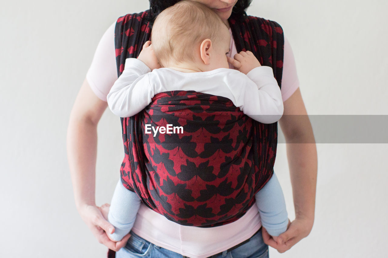 Midsection of woman carrying baby in harness