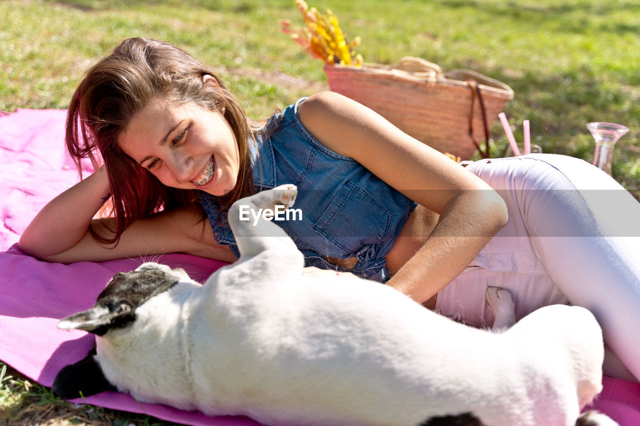 side view of young woman with dog sitting on field