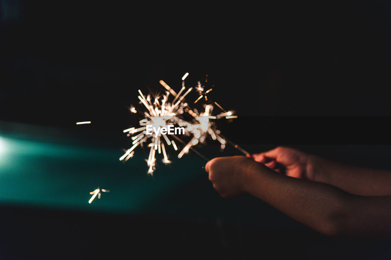 Person holding sparklers at night