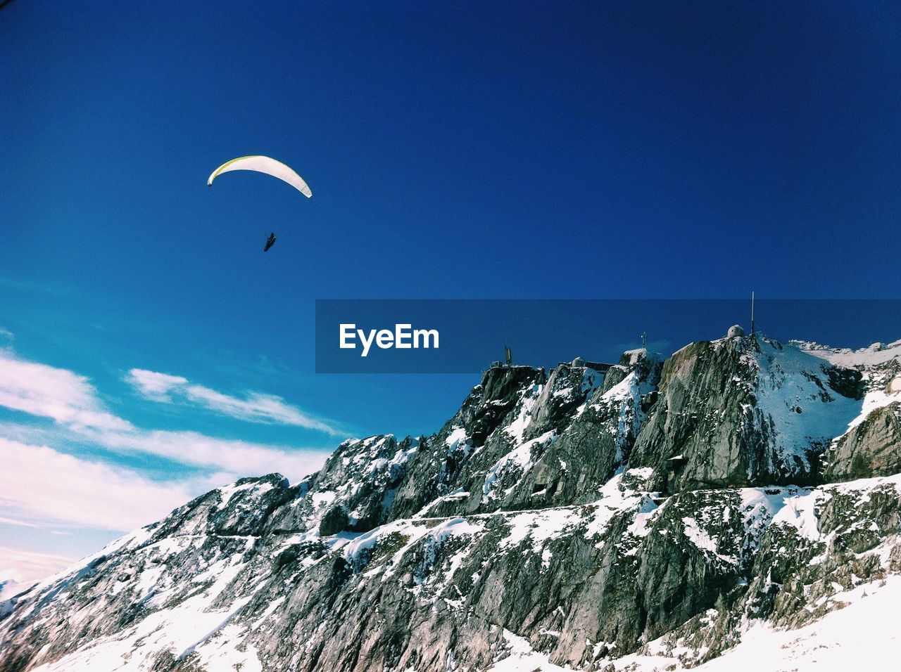 Person parasailing over snowcapped mountain