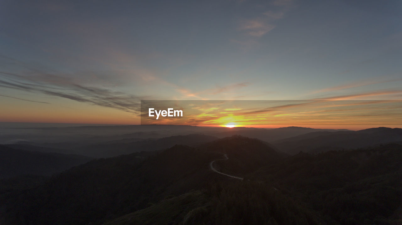 SCENIC VIEW OF SILHOUETTE MOUNTAINS DURING SUNSET