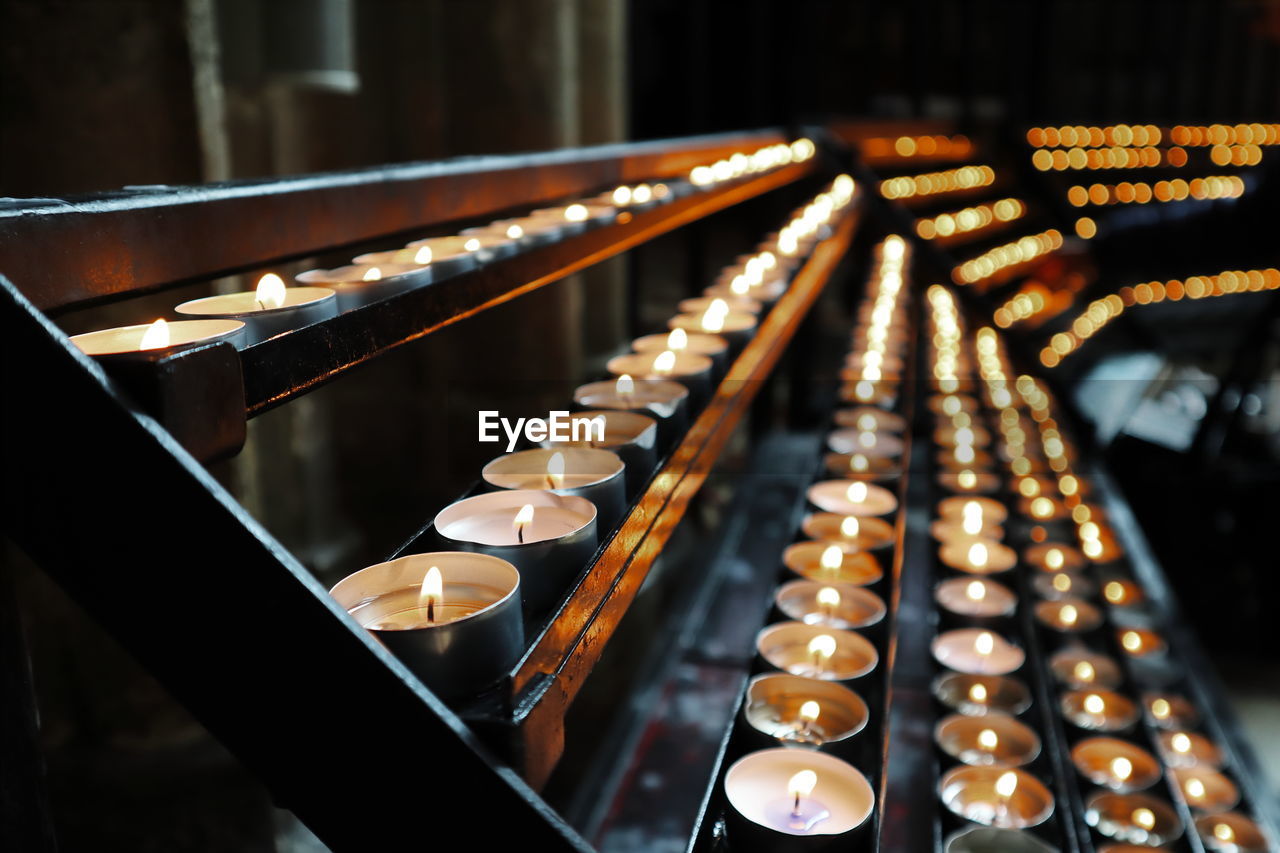 Lit tea light candles on shelves in church