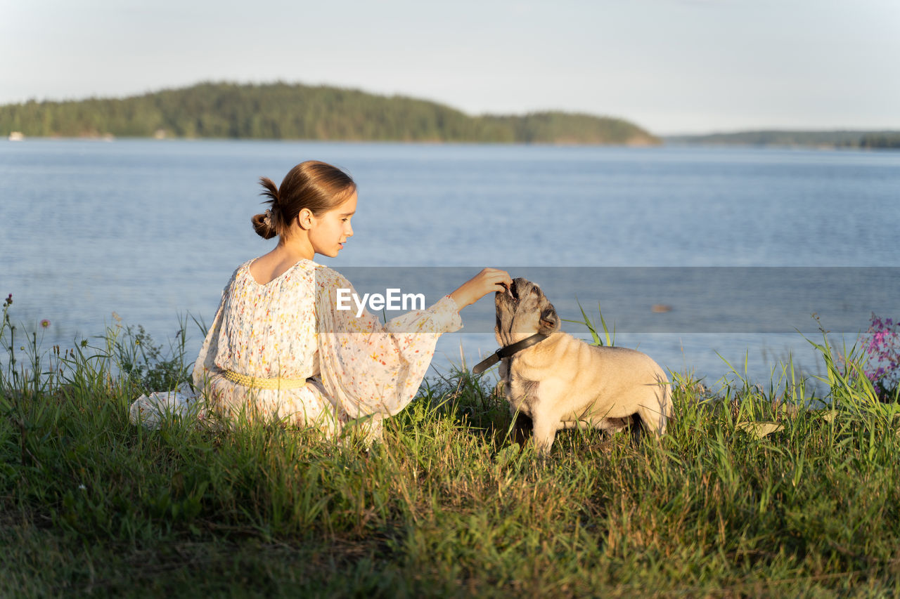 A girl and a pug on the lake shore