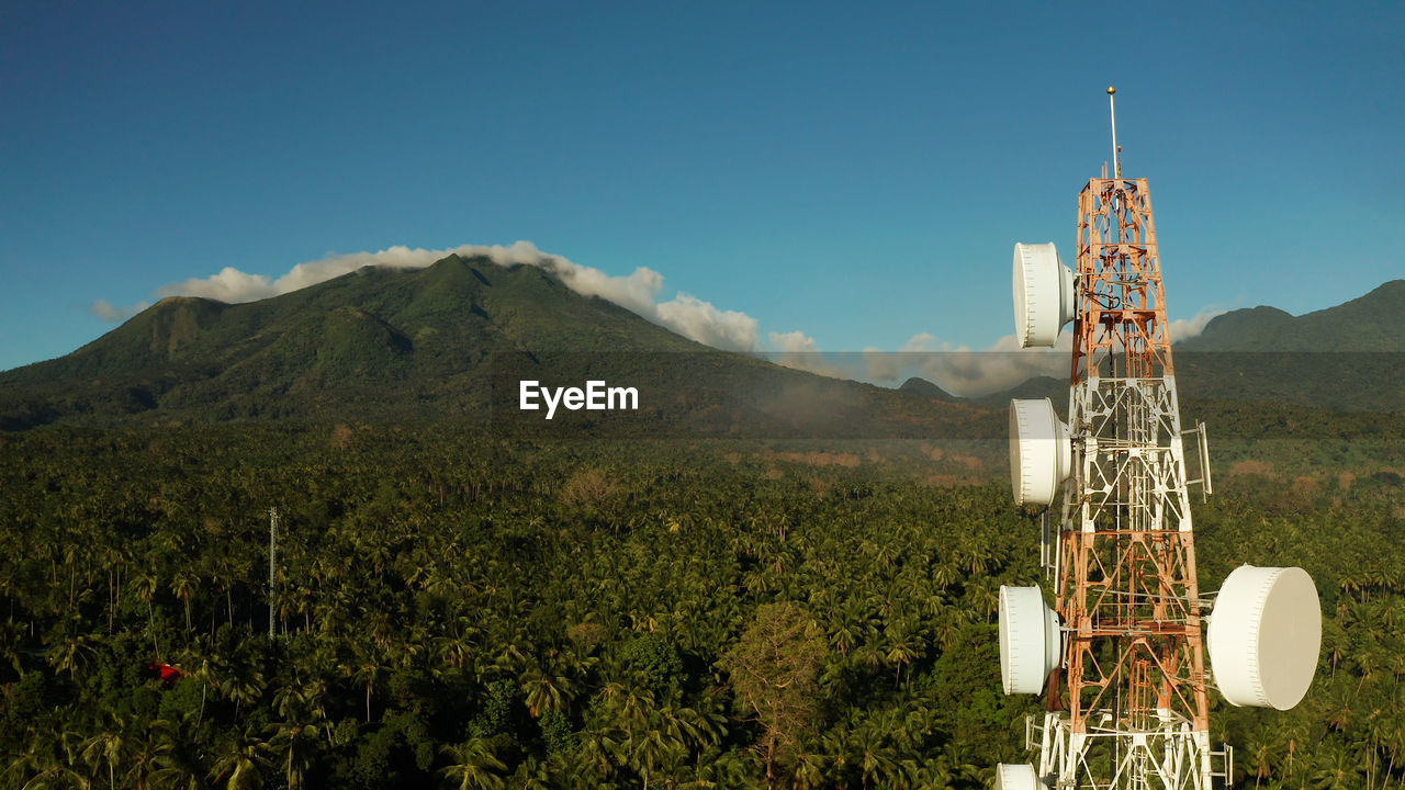 Telecommunication tower, communication antenna against mountains and rainforest, aerial view. 