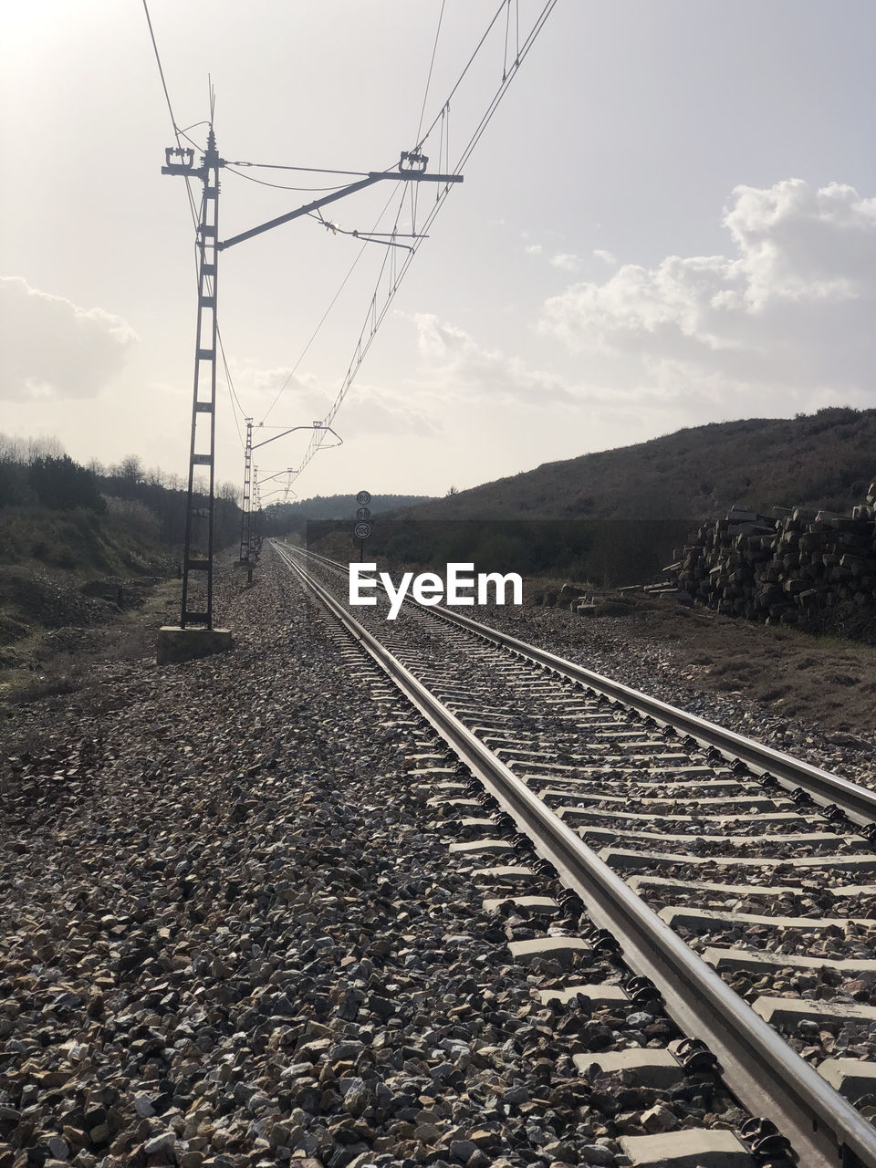 RAILROAD TRACKS BY ELECTRICITY PYLON AGAINST SKY