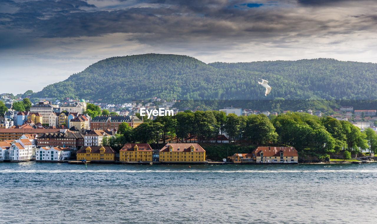 Town by river and mountains against sky