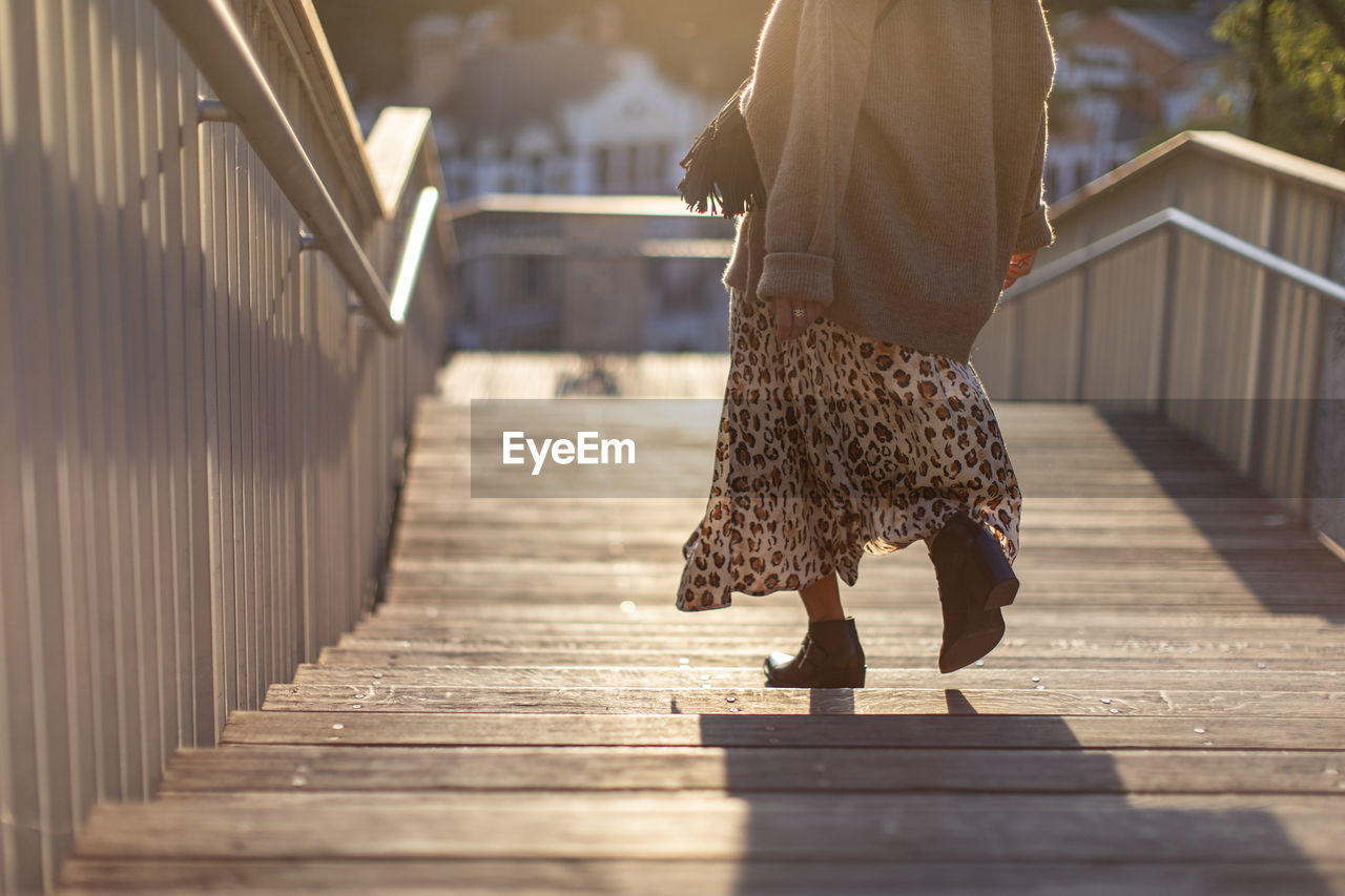 Low section of woman walking on footbridge