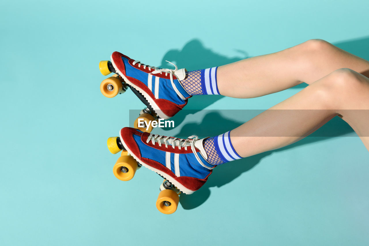 Low section of woman wearing skates over blue background