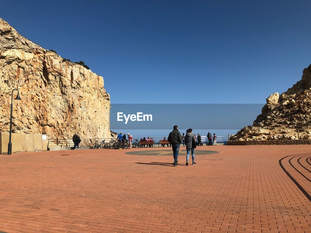 PEOPLE WALKING ON ROCKS AGAINST CLEAR SKY