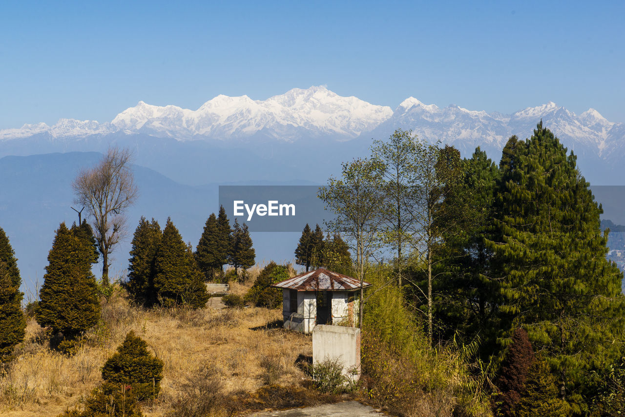 House amidst trees and kanchenjunga mountain range against sky