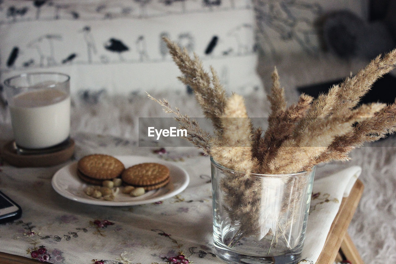 Close-up of breakfast by dry plant in glass on table