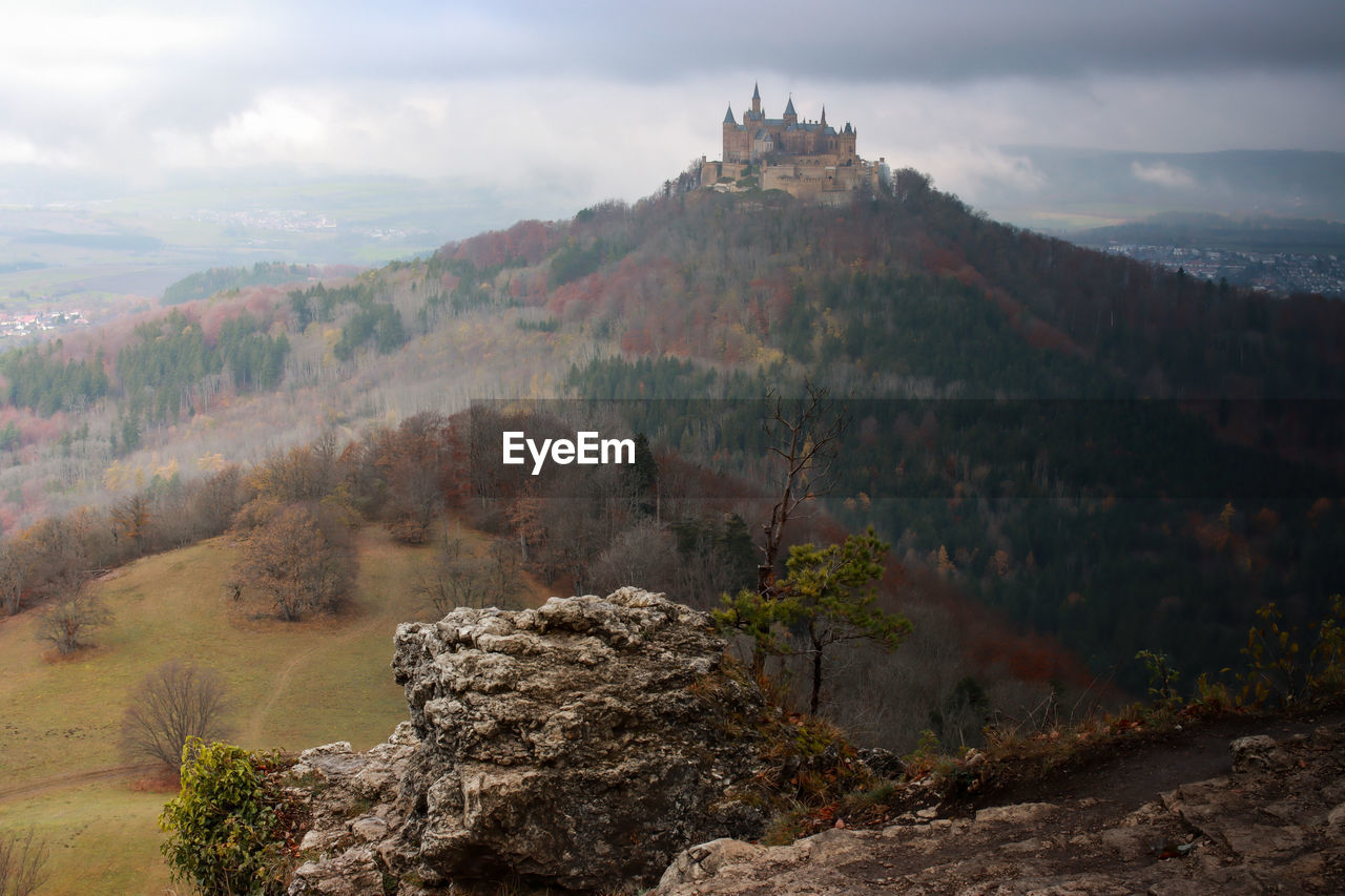 CASTLE ON MOUNTAIN AGAINST CLOUDY SKY