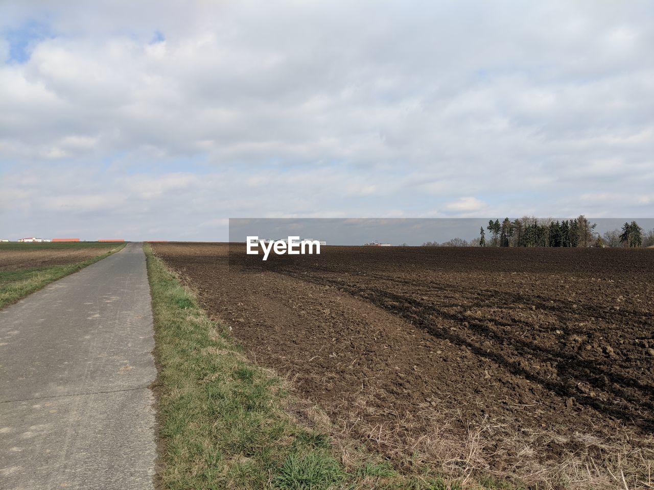 ROAD AMIDST AGRICULTURAL FIELD AGAINST SKY