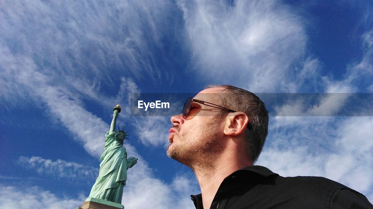 Woman by statue of liberty against sky