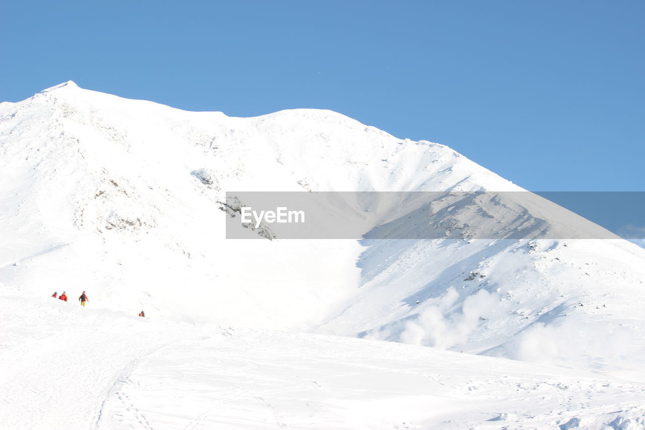 Scenic view of snowcapped mountains against clear blue sky