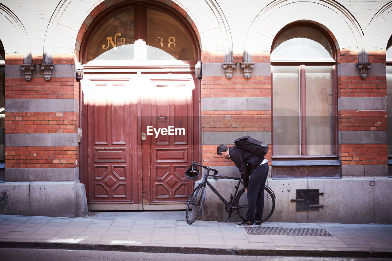 Full length of businessman with bicycle on sidewalk at city