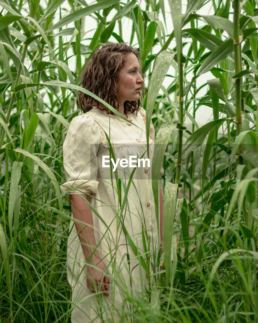 Woman looking away from camera while standing in field