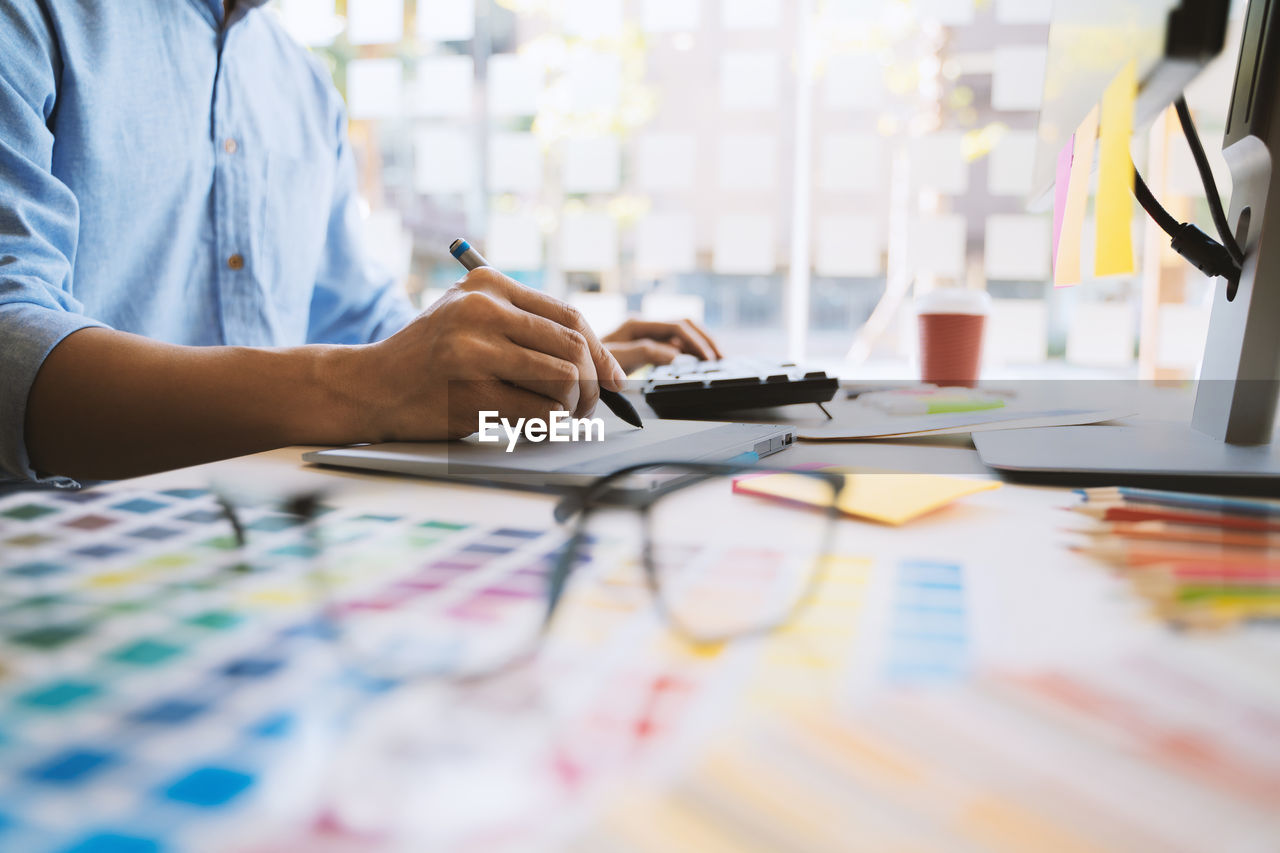 MIDSECTION OF MAN USING MOBILE PHONE