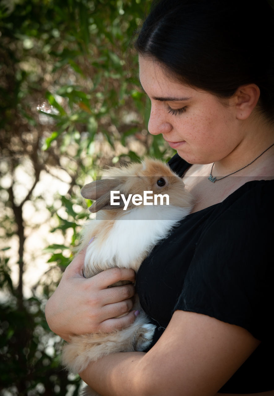 Young beautiful woman holding a black rabbit pet animal. domestic animal caring