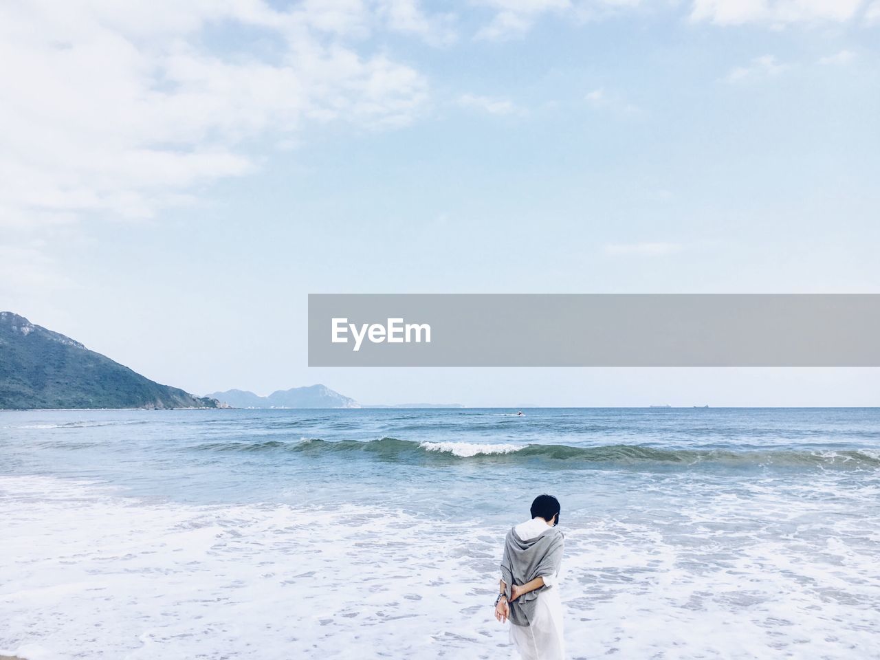 Rear view of man walking at beach against sky