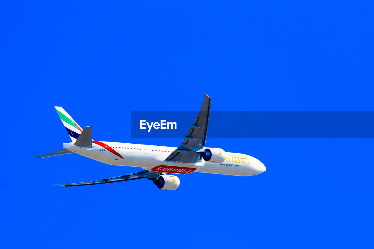 LOW ANGLE VIEW OF AIRPLANE WING AGAINST CLEAR BLUE SKY