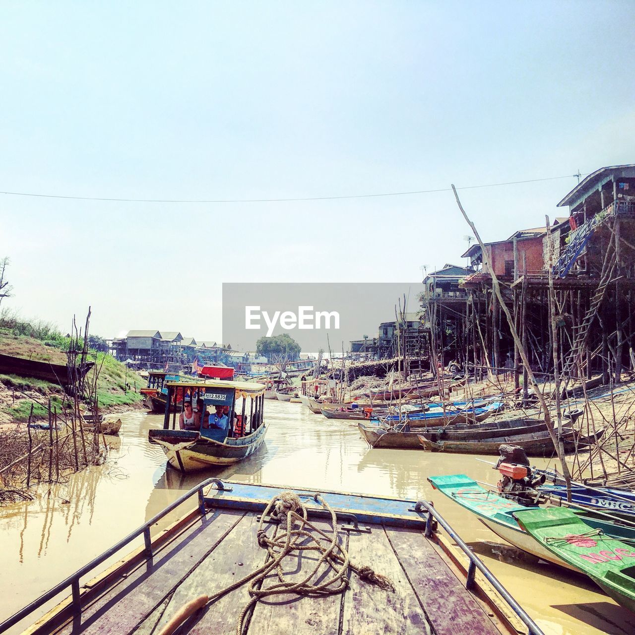 Boats moored in river by houses against clear sky