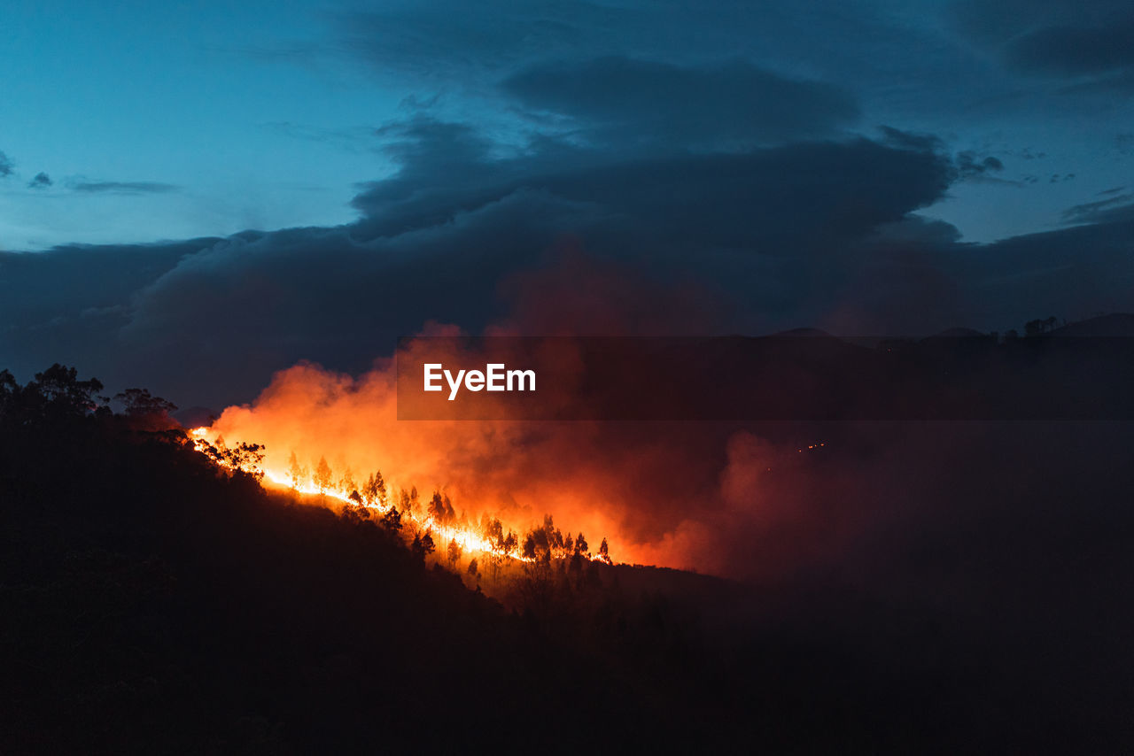 Countryside forest with cloudy sky covered by fire smoke during the evening