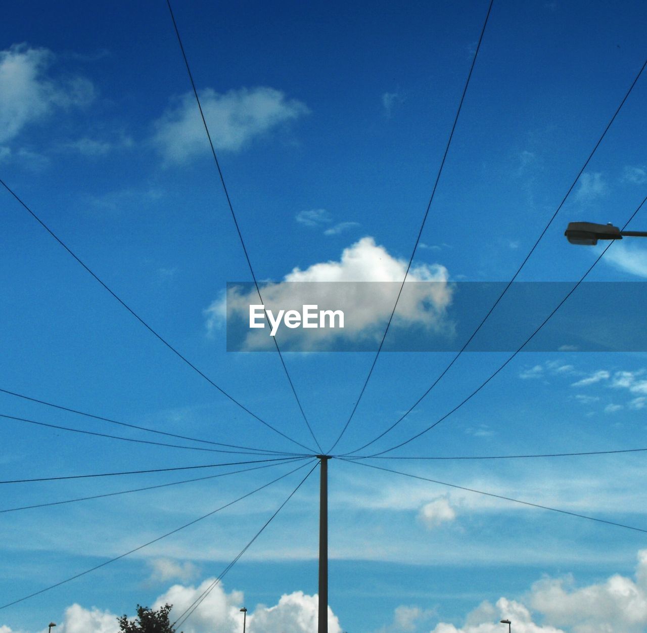 LOW ANGLE VIEW OF POWER CABLES AGAINST BLUE SKY