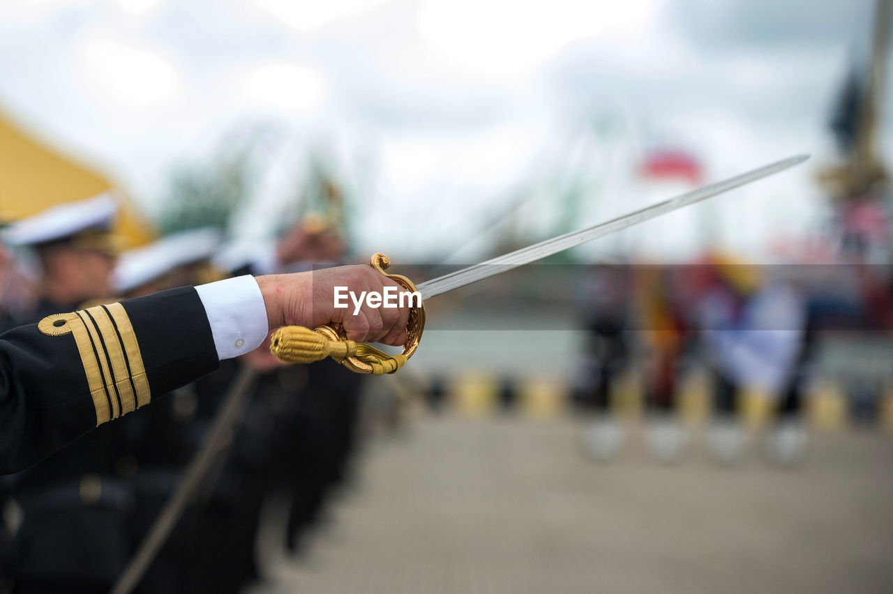 Cropped hand of army soldier holding sword outdoors