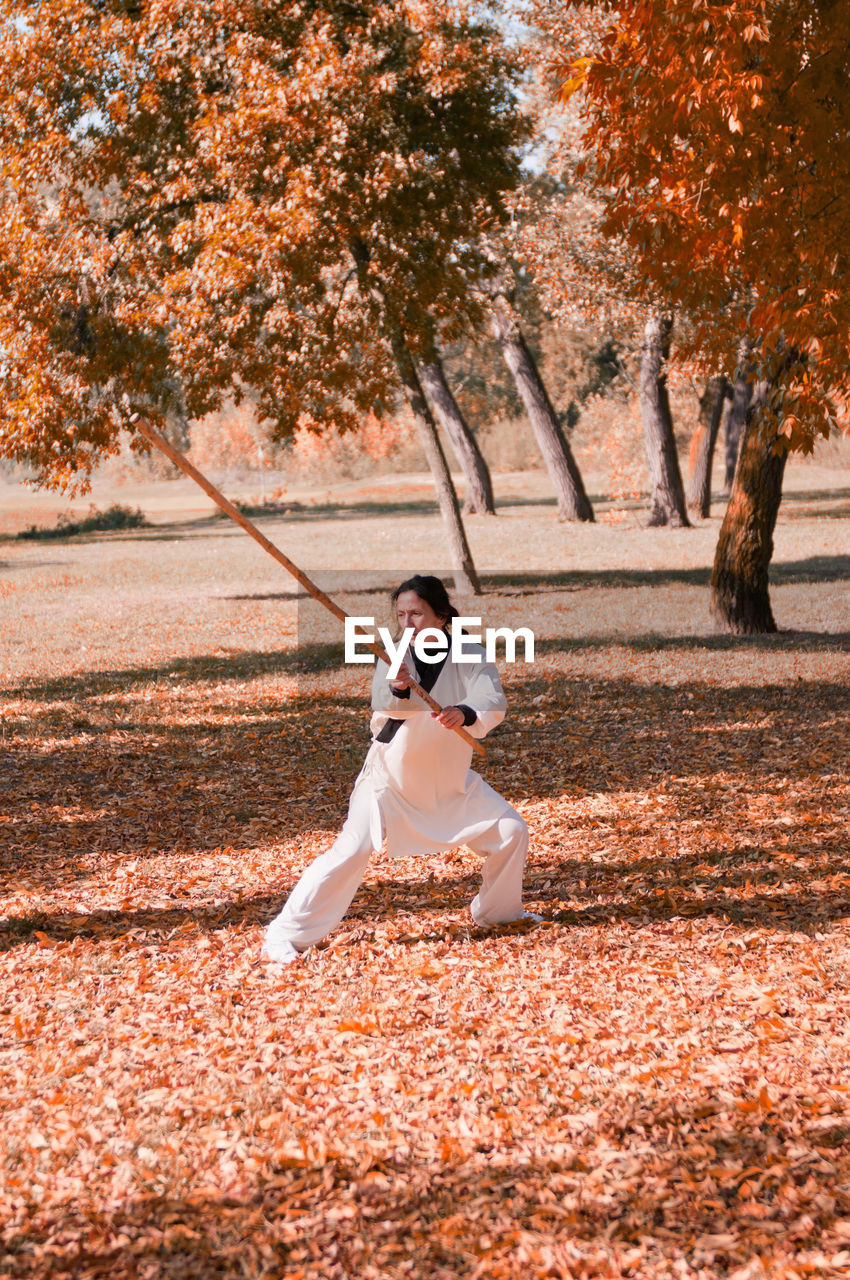 Woman practicing martial arts on autumn leaves