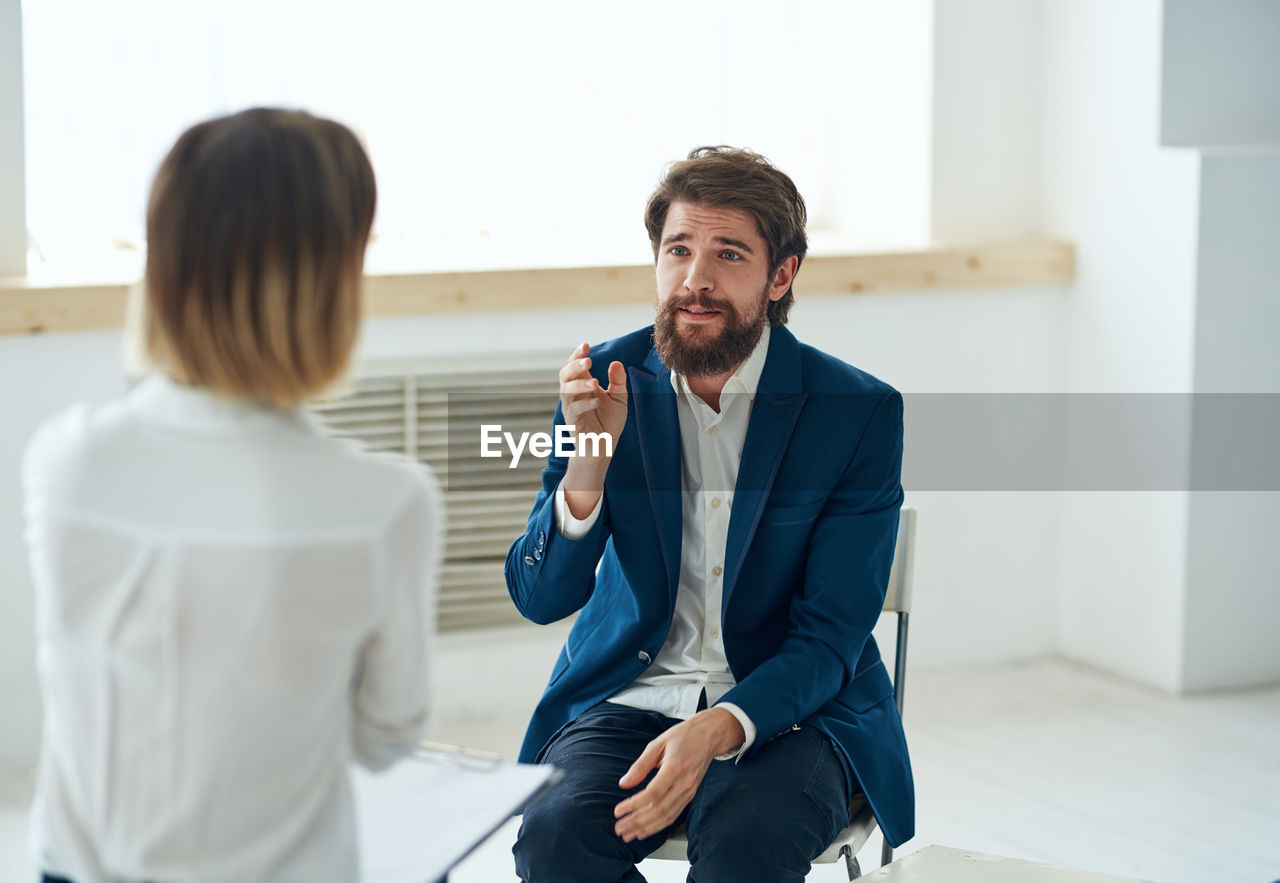 side view of businessman using phone while standing in office