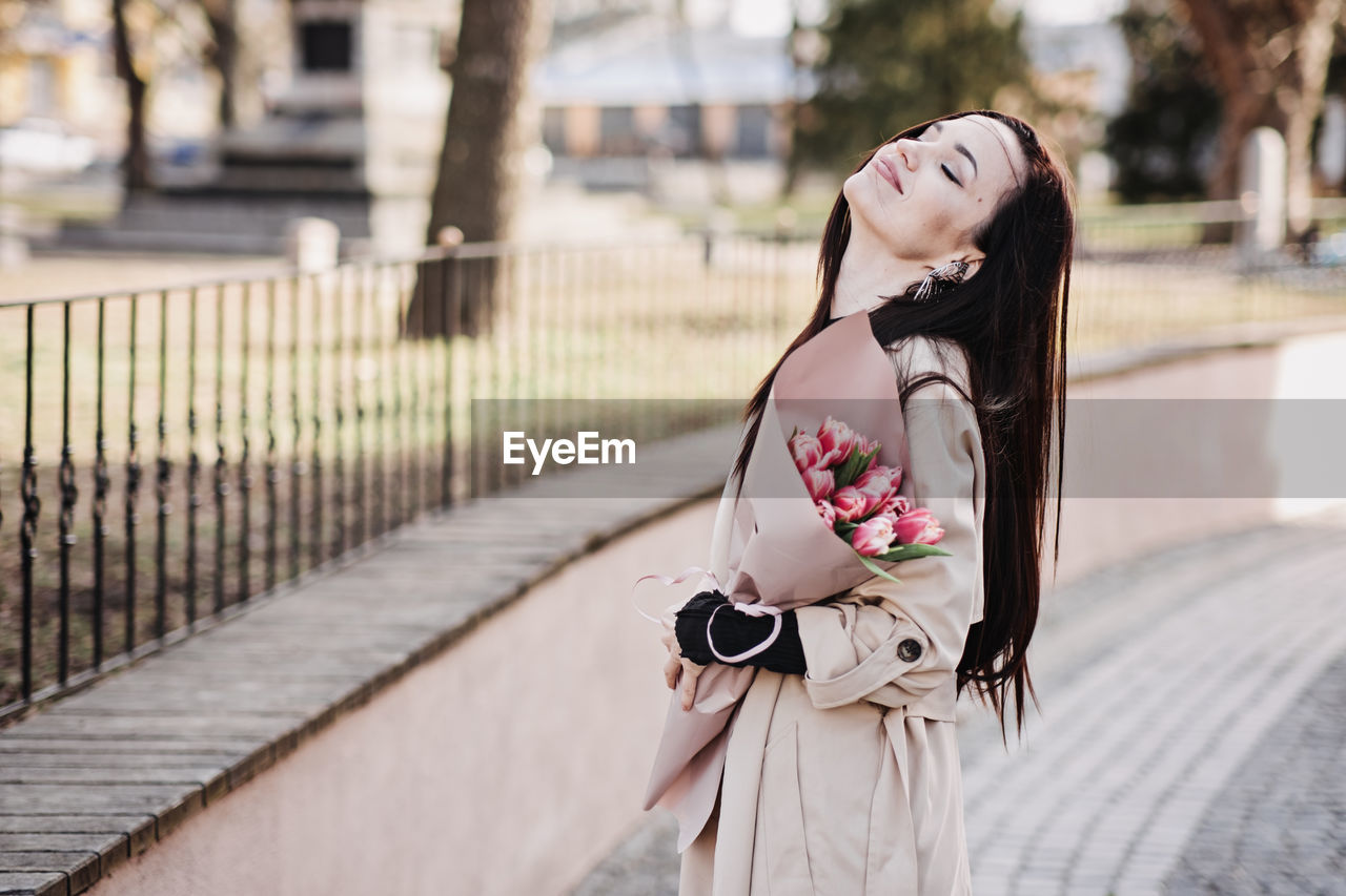 Spring, self love, self care. candid portrait of happy woman with tulips bouquet outdoors
