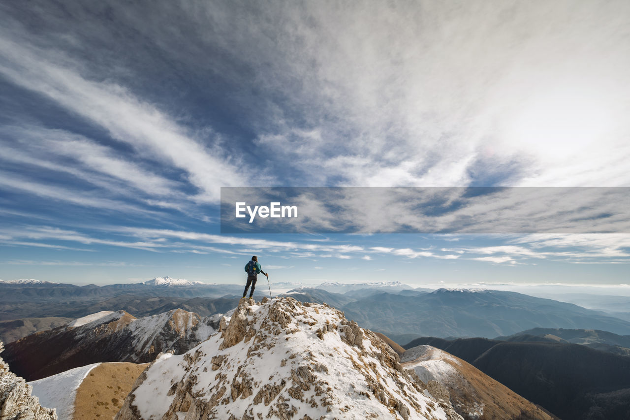 Rear view of woman on snowcapped mountain against cloudy sky